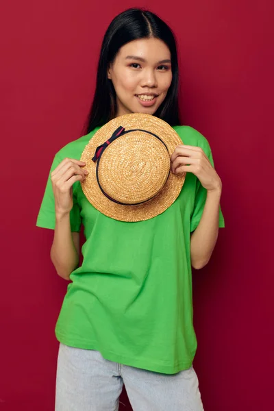 Жінка з азіатськими зовнішніми жестами з капелюхом у зеленій футболці Життєпис незмінним — стокове фото