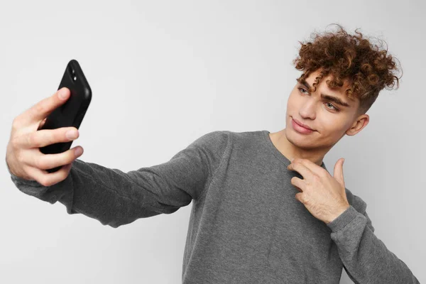 Bel ragazzo con un telefono in mano comunicazione sfondo isolato — Foto Stock