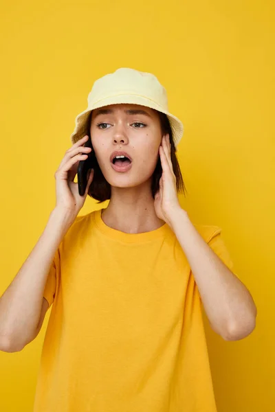 Jeune belle femme dans un chapeau jaune style jeune occasionnel parler au téléphone fond isolé — Photo