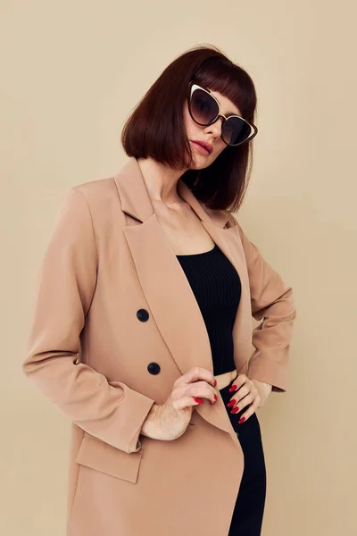 베이지 재킷을 입고우아 한 스타일의 선글라스 빛 배경을 한 여자의 사진 — 스톡 사진
