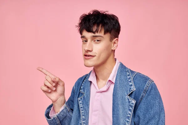 Retrato de un joven en la juventud ropa elegante chaqueta de mezclilla posando fondo rosa inalterado — Foto de Stock