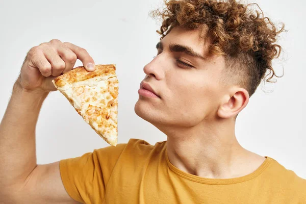 Jovem bonito em uma camiseta amarela comendo pizza Estilo de vida inalterado — Fotografia de Stock