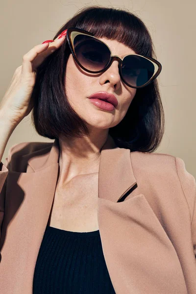 Hermosa mujer en gafas de sol traje de pelo corto gesto con las manos fondo claro — Foto de Stock