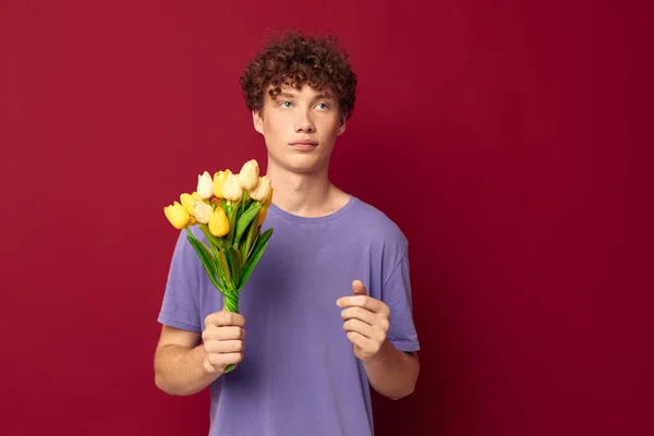 Молодий чоловік тримає жовтий букет з квітів фіолетових футболок ізольований фон незмінний — стокове фото