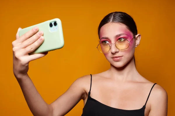 Ritratto di bella giovane donna sorriso rosa brillante trucco emozioni cosmetici smartphone selfie giallo sfondo inalterato — Foto Stock