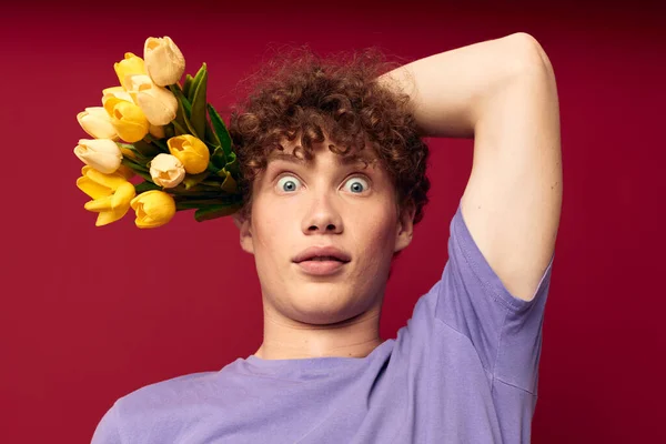 Mladý muž drží žlutou kytici květin fialové trička izolované pozadí beze změny — Stock fotografie