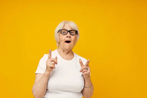 Elderly woman in a white t-shirt wears glasses isolated background — Stock Photo, Image