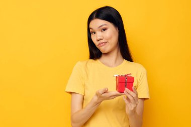 Çekici genç Asyalı kadın elinde bir hediye kutusu tutuyor. Arka planda bir değişiklik olmamış gibi duruyor.