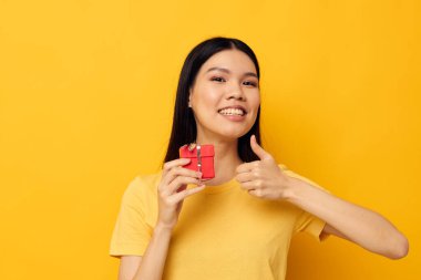Çekici genç Asyalı kadın Kırmızı hediye kutusu eğlenceli sarı arka plan değiştirilmemiş