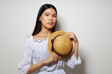 Beyaz gömlekli, yakışıklı, Asyalı bir kadın. Şapka modasında. Arka planda değişiklik yok.