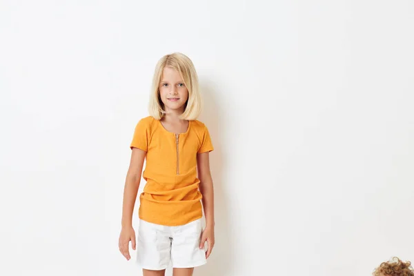 Κοριτσάκι με ξανθά μαλλιά σε κίτρινο μπλουζάκι απομονωμένο φόντο — Φωτογραφία Αρχείου