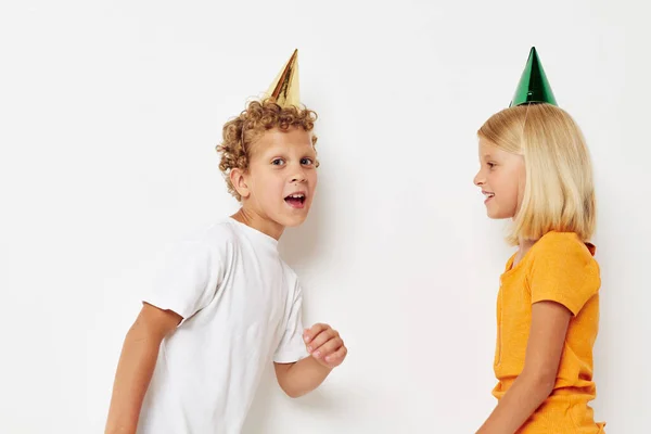 Niño y niña en casquillos multicolores cumpleaños fiesta emoción fondo claro —  Fotos de Stock