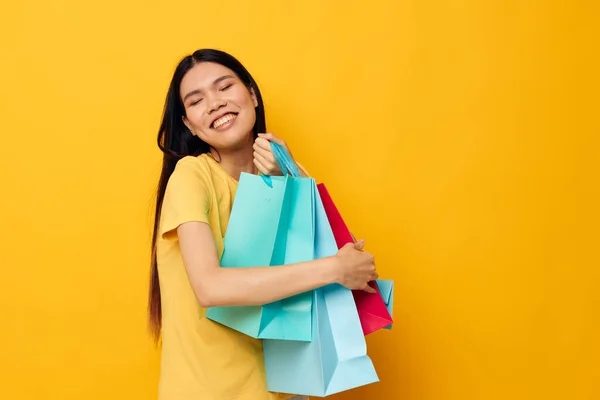 Жінка в жовтій футболці з різнокольоровими сумками для покупок ізольований фон незмінний — стокове фото