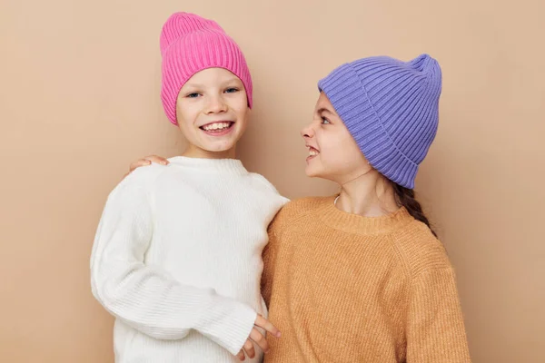 Twee grappige meisjes knuffelen poseren kleurrijke hoeden — Stockfoto