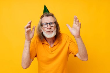 Yaşlıların portresi. Eğlenceli bir doğum günü şapkası. Kafasında izole bir arka plan.