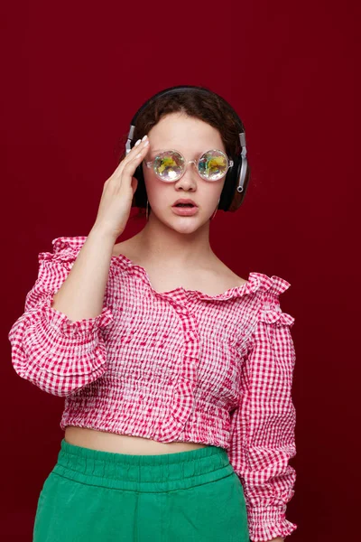 Mulher de blusa rosa e shorts verdes ouvindo música com fones de ouvido — Fotografia de Stock