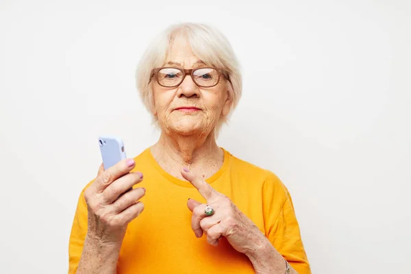 노란 티셔츠를 입고 전화를 걸어 친밀 한 감정으로 소통하는 노부인 — 스톡 사진