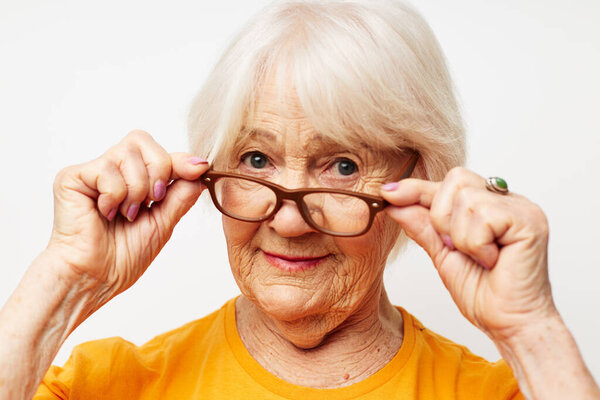 Portrait of an old friendly woman vision problems with glasses light background