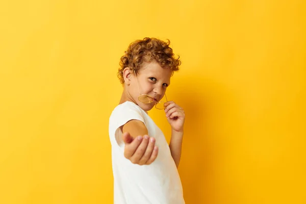 Retrato de la foto niño rizado en una camiseta blanca con gafas haciendo gestos con las manos aisladas fondo inalterado — Foto de Stock