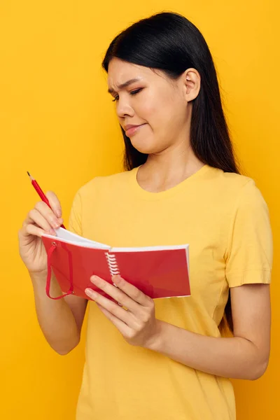 Femme avec l'apparence asiatique dans un t-shirt jaune carnet rouge modèle studio d'entraînement inchangé — Photo