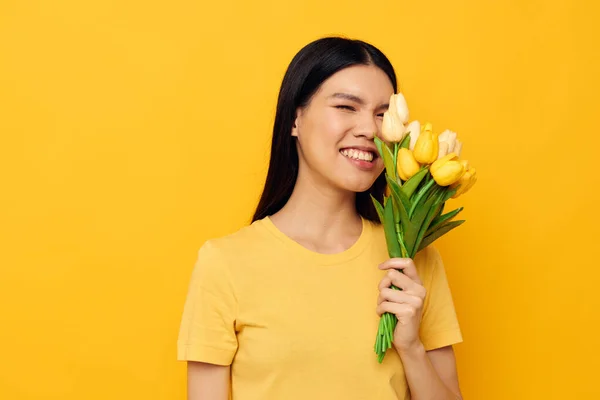 노란 꽃 꽃다발을 들고 있는 아시아인아름다운 젊은 여자의 모습은 변함 이 없는 배경으로 외따로 떨어져 있다 — 스톡 사진