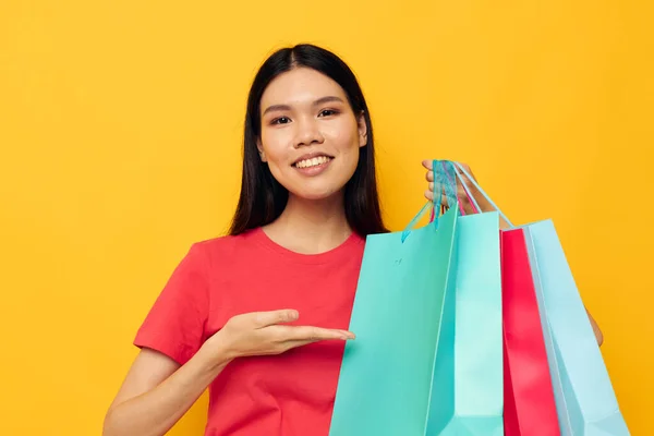 Portret Aziatische mooie jonge vrouw met veelkleurige boodschappentassen gele achtergrond ongewijzigd — Stockfoto