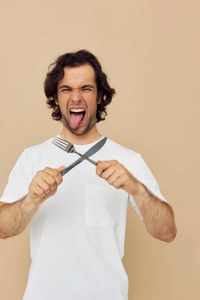 Hombre en una camiseta blanca con cuchillo con tenedor Lifestyle inalterado — Foto de Stock