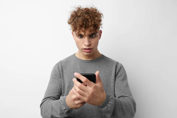 Кучерявий хлопець дивиться на моду телефону ізольований фон — стокове фото