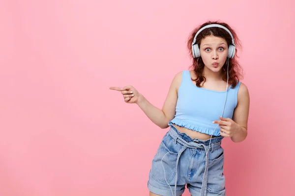 Fröhliches Mädchen mit Kopfhörern posiert Musik rosa Hintergrund Unterhaltung unverändert — Stockfoto