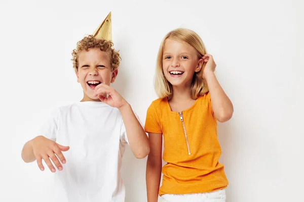 Niño y niña en casquillos multicolores cumpleaños fiesta emoción fondo claro —  Fotos de Stock