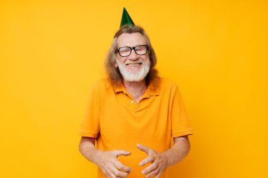 Sarı tişörtlü, kafasında şapkası olan emekli yaşlı bir adamın fotoğrafı.