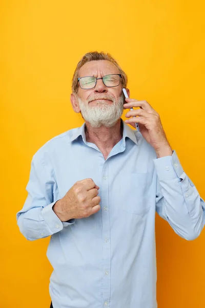 Old man talking on the phone emotions yellow background — Stock Photo, Image