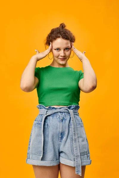 Menina bonito em um verde gestos t-shirt com as mãos emoções fundo amarelo — Fotografia de Stock