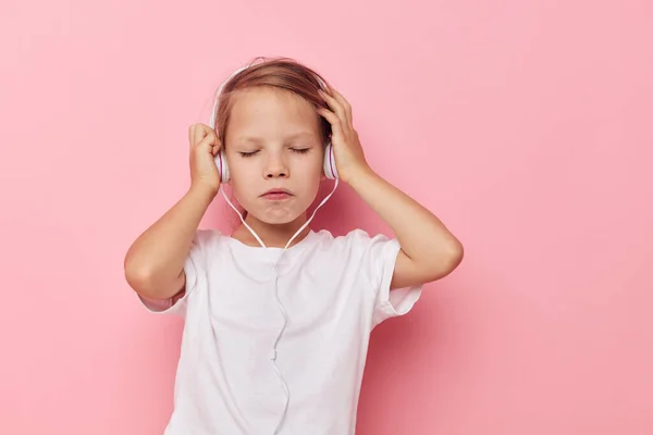 Petite fille dans un t-shirt blanc avec casque fond rose — Photo