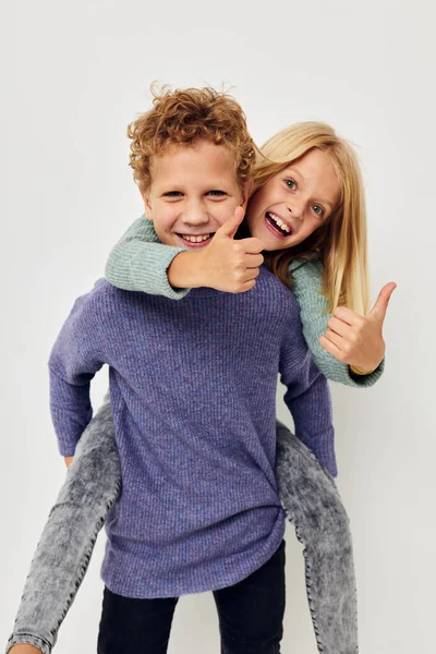 Little boy and girl in multi-colored sweaters posing for fun light background — Stock fotografie