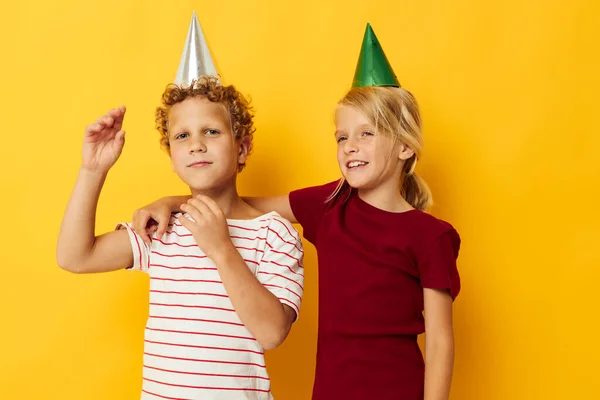 Kleine kinderen vakantie plezier met caps op je hoofd gele achtergrond — Stockfoto