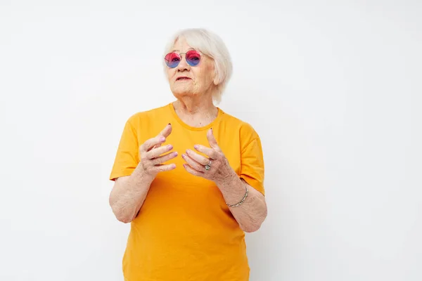 Gözlüklü, emekli yaşlı bir kadının fotoğrafı. El hareketleriyle izole edilmiş arka plan. — Stok fotoğraf