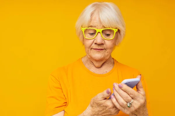 Foto de la vieja señora jubilada divertido hablando en el fondo amarillo del teléfono — Foto de Stock