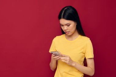 Kadın telefonu kırmızı arka planda kullanıyor.