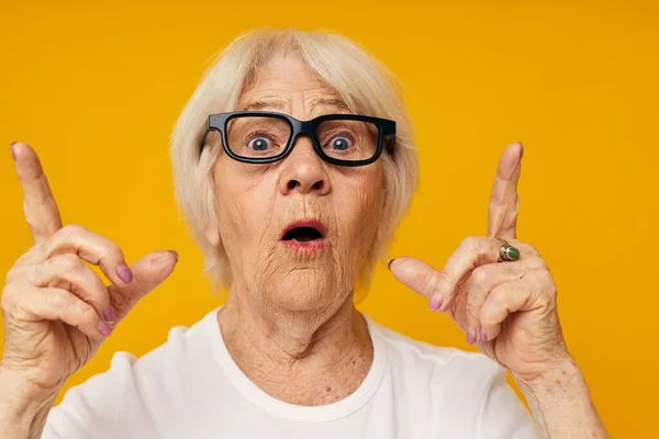 笑顔のおばあちゃんカジュアルなTシャツと眼鏡黄色の背景 — ストック写真