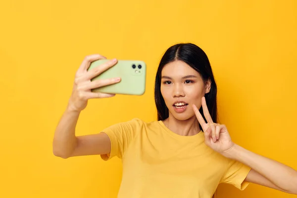 Όμορφη μελαχρινή με ένα τηλέφωνο στα χέρια της κάνει μια selfie απομονωμένη φόντο αμετάβλητη — Φωτογραφία Αρχείου