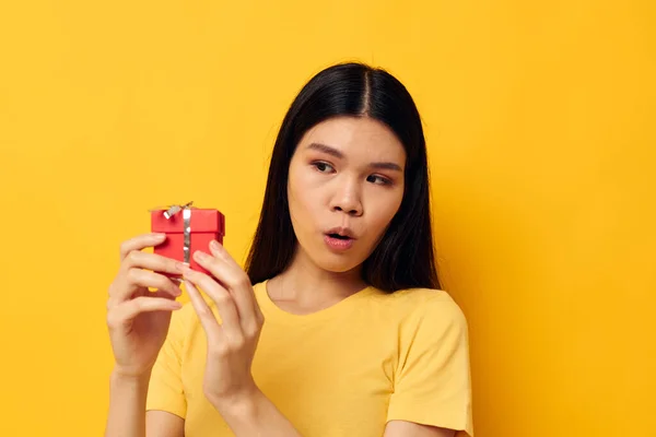 Donna con aspetto asiatico piccolo rosso regalo scatola divertimento giallo sfondo inalterato — Foto Stock