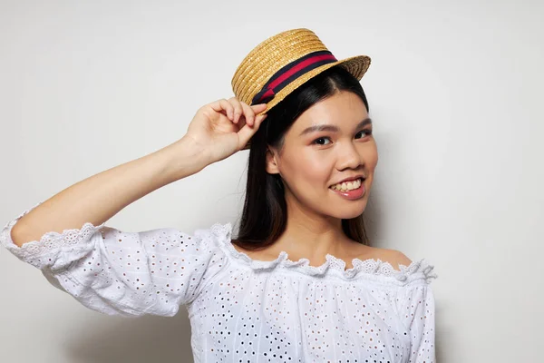 Mulher com aparência asiática chapéu na mão posando sorriso luz fundo inalterado — Fotografia de Stock