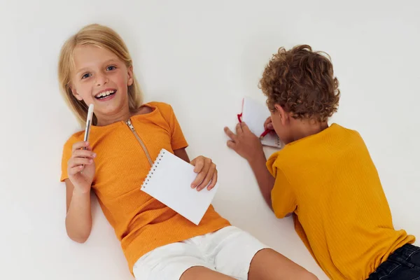 Cheerful children drawing in notebooks lying on the floor childhood lifestyle unaltered — Stockfoto