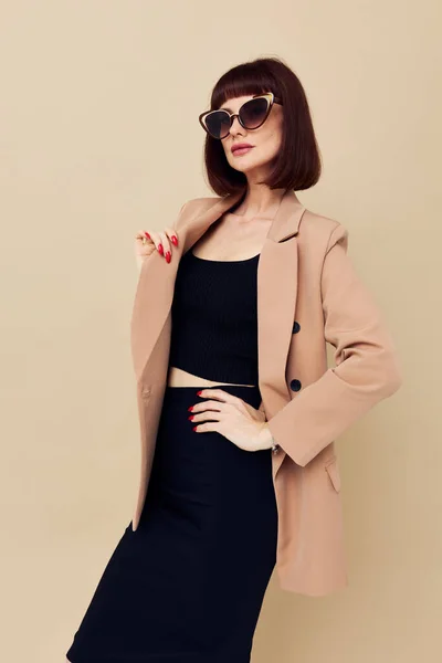 Atrakcyjna kobieta w beżowej kurtce elegancki styl okulary przeciwsłoneczne odizolowane tło — Zdjęcie stockowe
