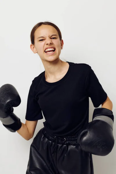 Jovem mulher em luvas de boxe em calças pretas e um fundo luz camiseta — Fotografia de Stock