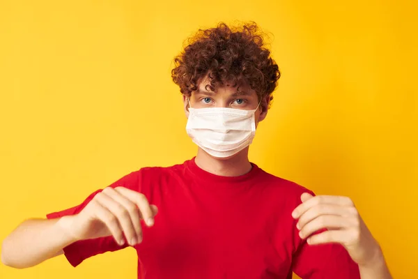 Retrato de um jovem encaracolado em uma camiseta vermelha máscara médica proteção tiro monocromático — Fotografia de Stock
