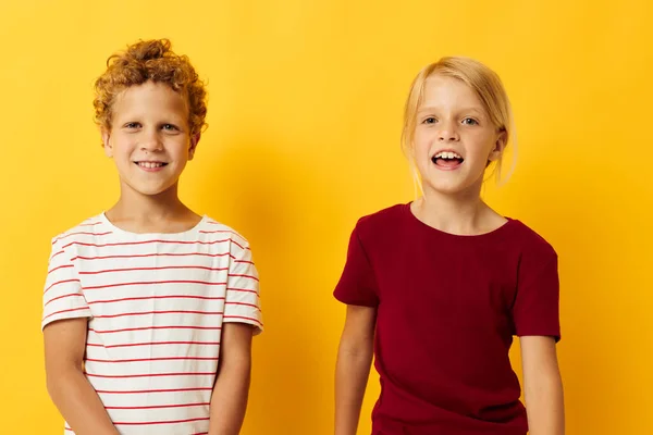 유행하는 아동기 오락의 노란 배경을 꼭 껴안고 있는 즐거움을 주는 두 어린이 — 스톡 사진