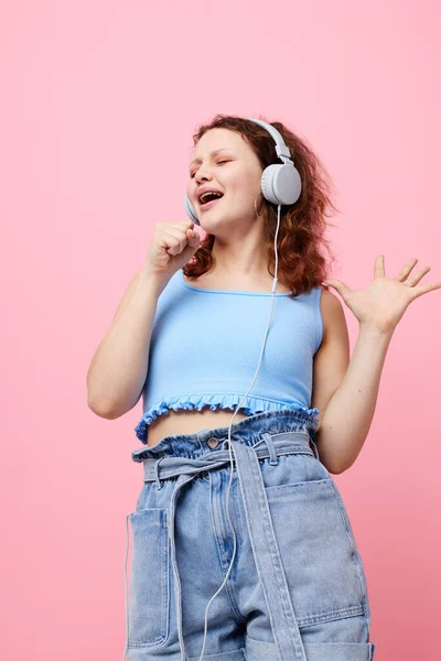 Όμορφη γυναίκα φορώντας ακουστικά απόσπαση της προσοχής μόδας χορό ροζ φόντο αμετάβλητη — Φωτογραφία Αρχείου