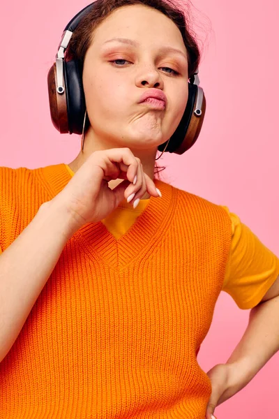 Mooie vrouw in een oranje trui hoofdtelefoon muziek entertainment bijgesneden uitzicht ongewijzigd — Stockfoto